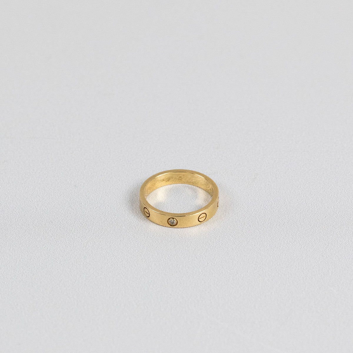 Gros plan sur le diamant serti clos d’une bague Cartier Love en or