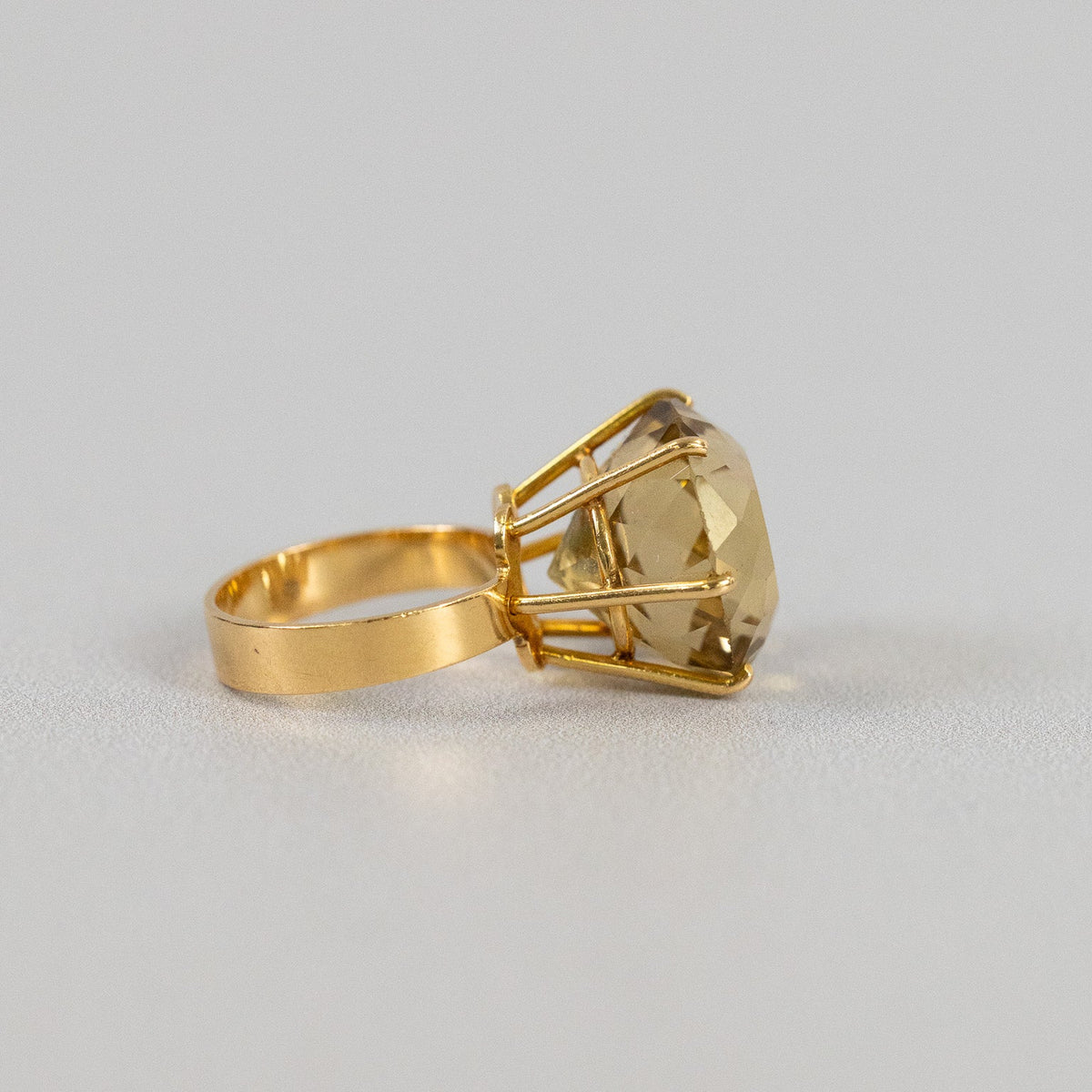 Reflets dorés et facettes lumineuses de la citrine d’une bague vintage en or jaune, à la lumière naturelle