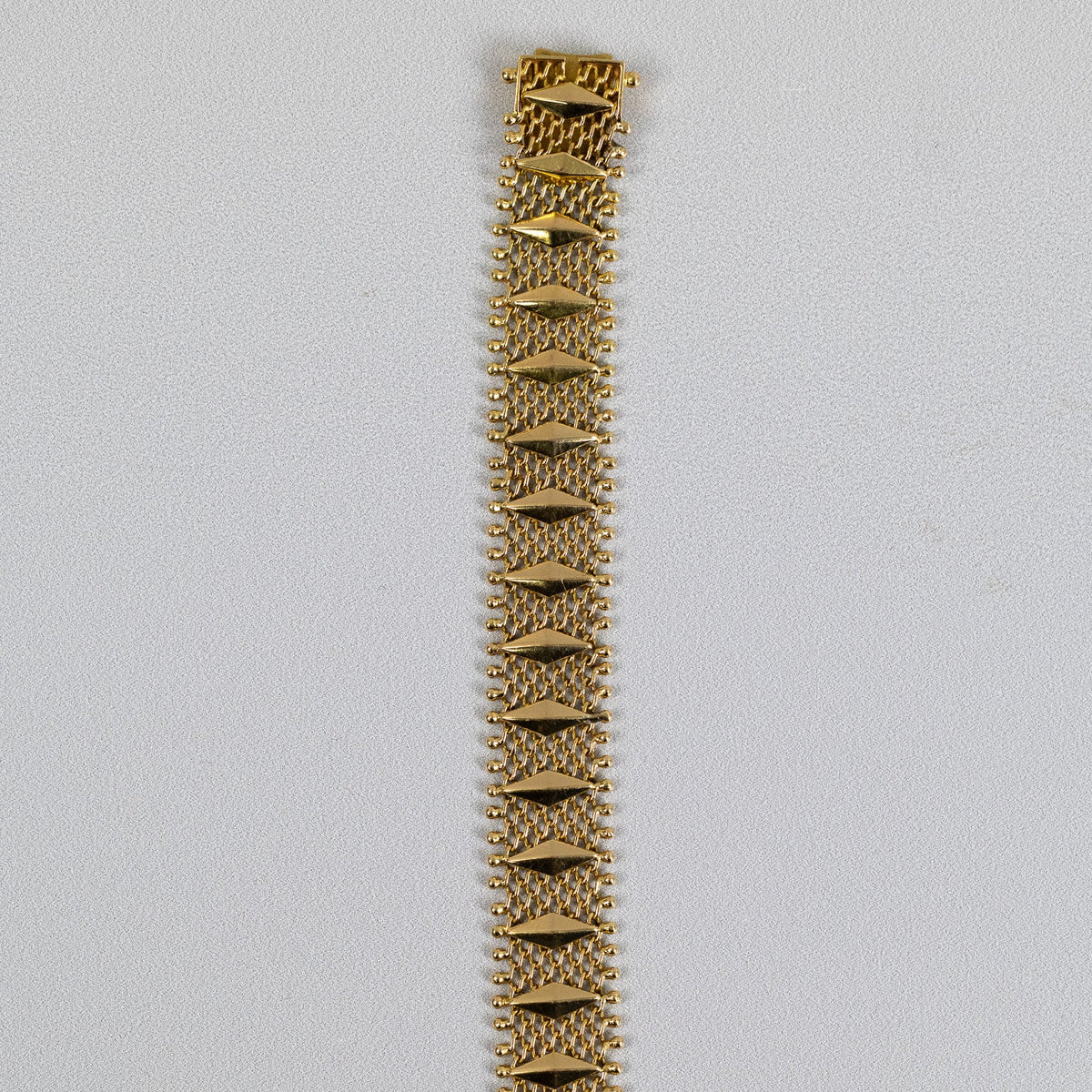 Détail des losanges facettés et de la maille ajourée du bracelet en or jaune