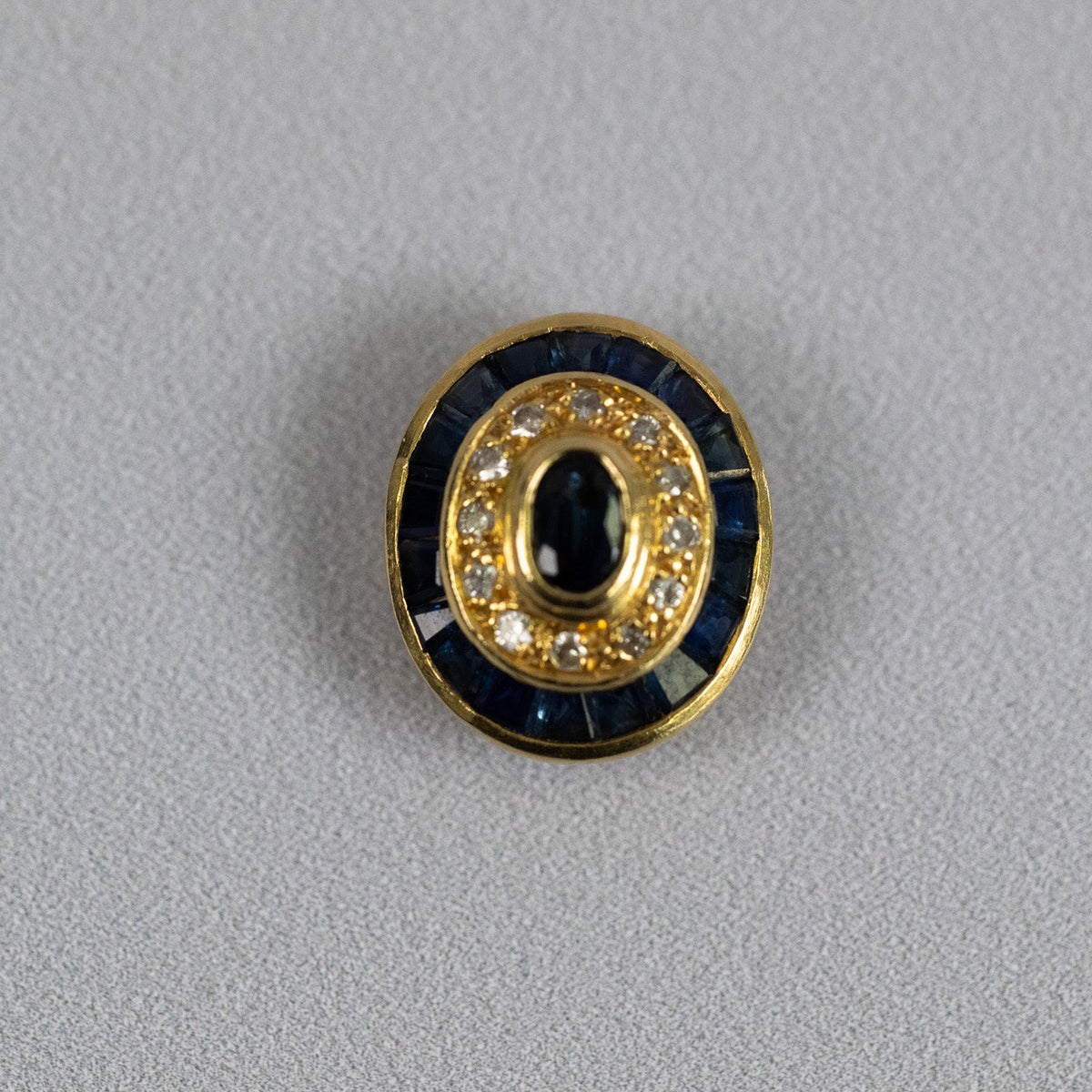 Saphir taille ovale en serti clos entouré de diamants sur pendentif en or jaune