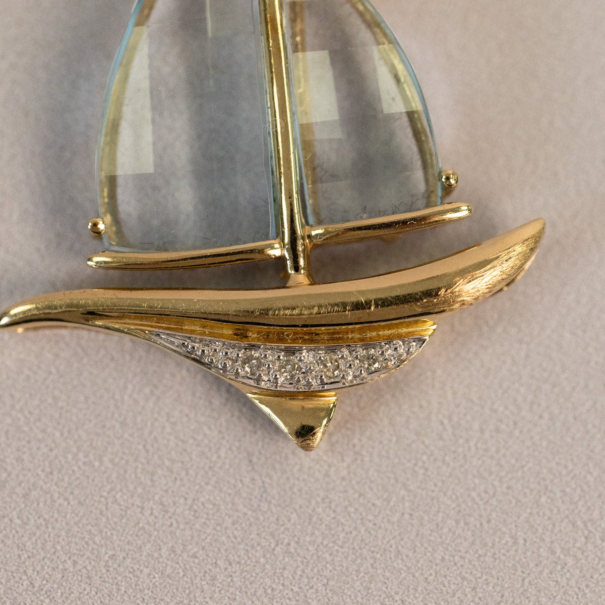 Détail de la coque en or jaune et du pavage serti sur or blanc d’un pendentif voilier vintage